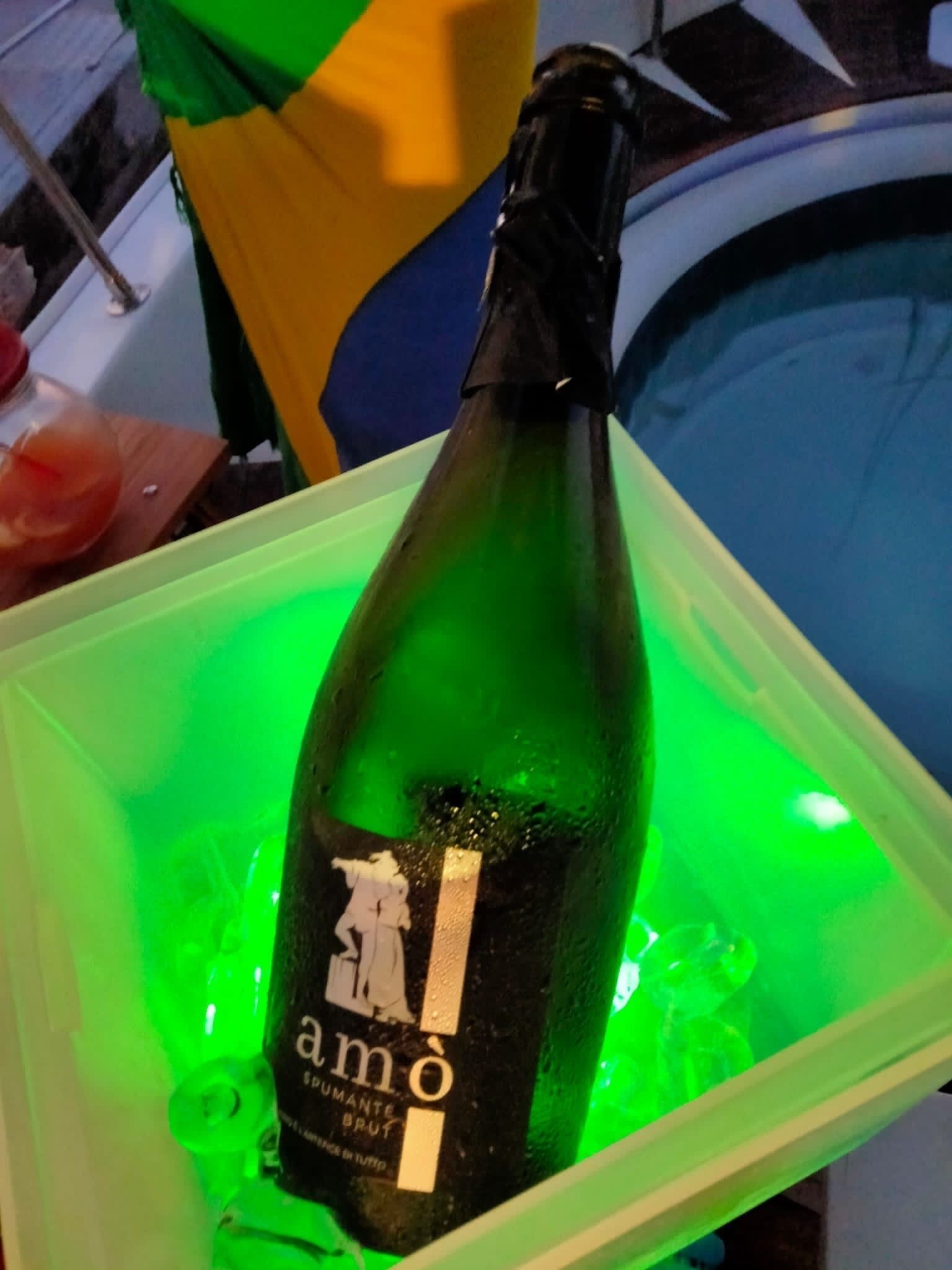 A bottle of 'amô' champagne in a green container.