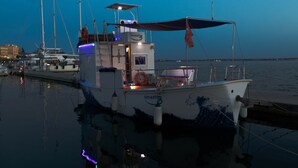 A boat docked at a marina with a covered cabin and a small deck area. - AMAZING in Ortigia  (Siracusa)