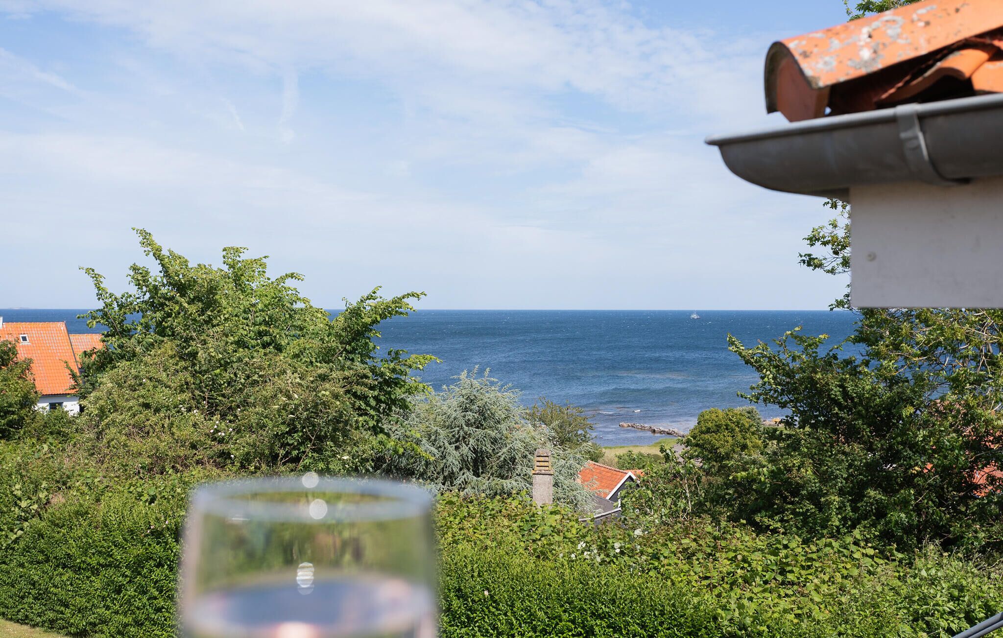 A coastal view with a clear sky, a body of water, and greenery.