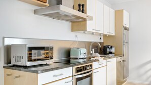 Cocina moderna con microondas, tostadora y cafetera integradas, además de refrigerador y armarios de madera.