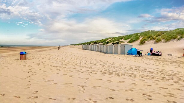 Ein Strand mit mobilen Toiletten und einem aufgebauten Zelt im Sand.