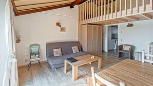 Ein Wohnzimmer mit einer Couch, einem Couchtisch und einem Esstisch. Eine Treppe führt auf eine obere Ebene.