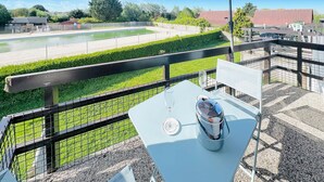 Ein Balkon mit Tisch und Stühlen, mit Blick auf einen Swimmingpool und einen Garten.