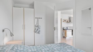 A bedroom with a bed, a wardrobe, a bathroom, and a kitchenette. - Gudhjem Søpark Lejl. 12 (Gudhjem)