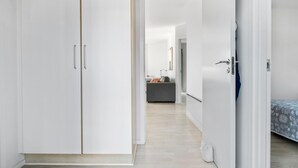 A hallway leading to a bedroom with a bed, a wardrobe, and a desk area. - Gudhjem Søpark Lejl. 12 (Gudhjem)