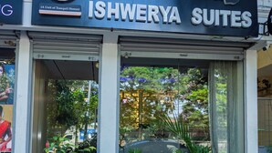 The exterior of Ishwerya Suites with a signboard, entrance, and surrounding greenery. - Ishwerya Suites (Bengaluru)