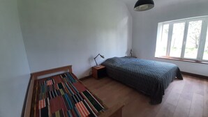 Un dormitorio con cama, escritorio, silla, ventana y lámpara colgante.