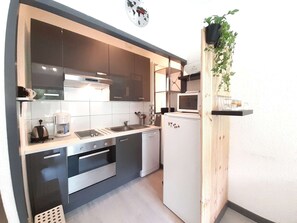 Une cuisine compacte équipée d’un four à micro-ondes, d’un évier, d’une cuisinière et d’un petit réfrigérateur.