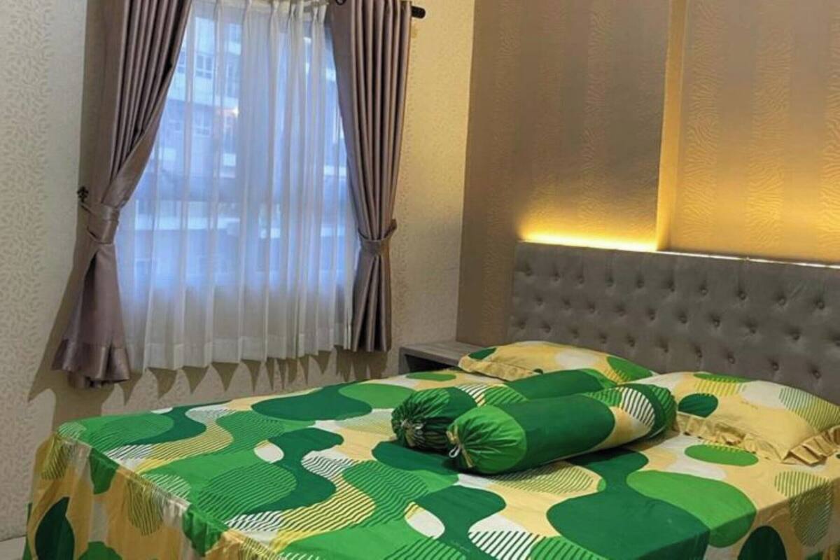 A room with a bed, a window with curtains, and a wall with a textured pattern.