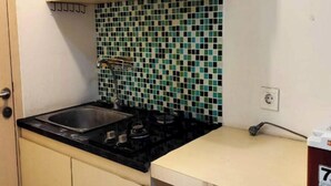 A kitchen with a gas stove, a sink, and a tiled backsplash. - OYO 94087 Apartemen 19 Avenue By Rh (Jakarta)