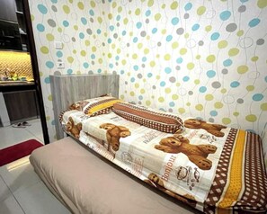 Ein Zimmer mit einem Bett, einem roten Teppich und einer Wand mit einem Punkte-Muster.
