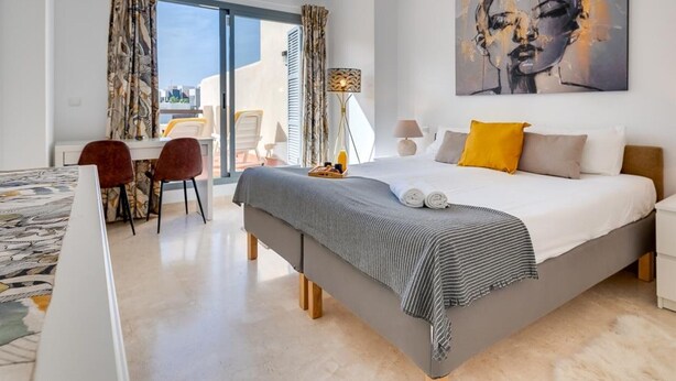 Een moderne hotelkamer met een groot bed, een bureau en uitzicht op de stad.