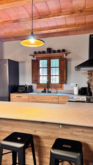 Una cocina moderna con armarios de madera, un microondas integrado y una isla grande con taburetes.