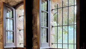 A stone wall with two arched windows, one open, and a tiled floor. - More Morrenyà - Rural House Garrotxa (Sant Jaume de Llierca)