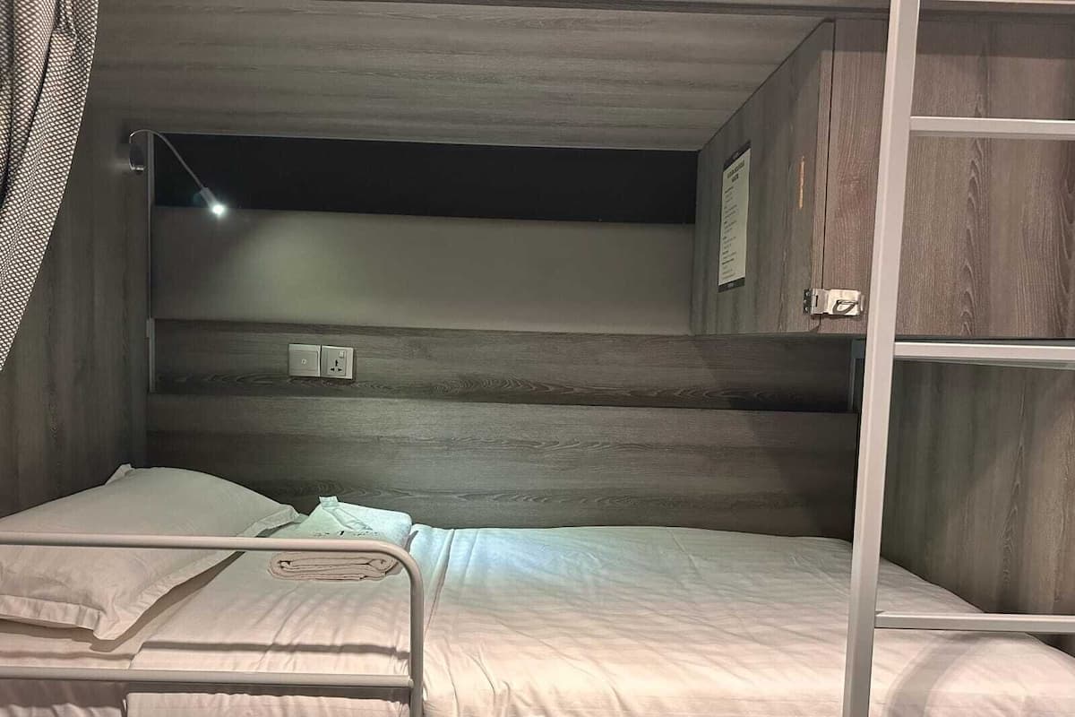 A bunk bed with a wooden headboard and a small shelf above it.