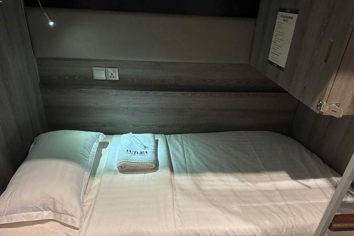 A bunk bed with a folded towel labeled "FUTURA" and a sign indicating "FUTURA BOUTIQUE HOSTEL".