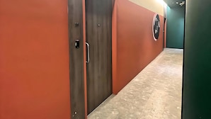Un couloir avec une enseigne bleue indiquant la sortie, une porte portant le numéro 23 et un sol à motifs.