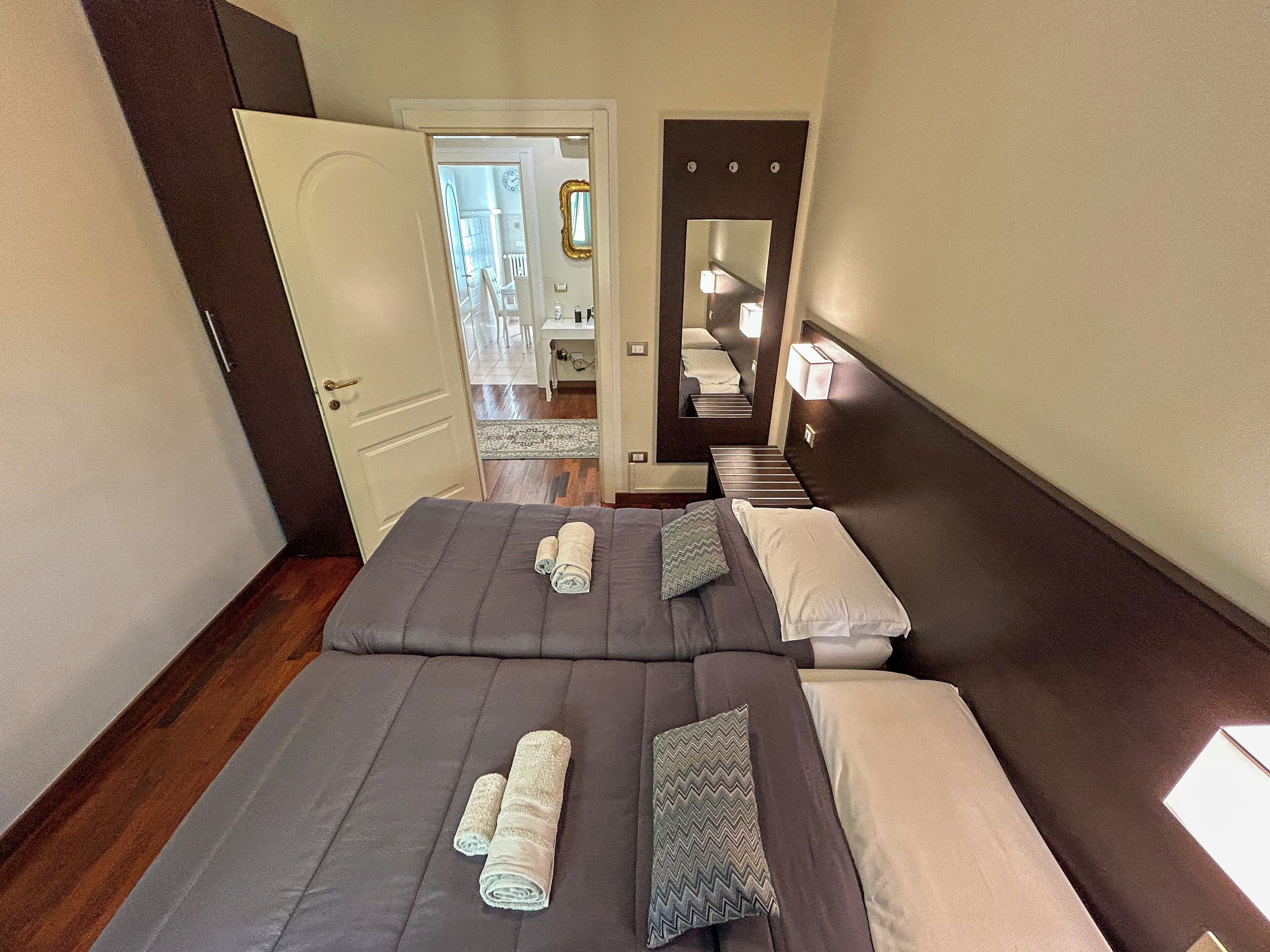 A hotel room with two beds, a mirror, and a door leading to a hallway.