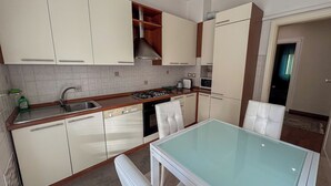 A compact kitchen with white cabinets, a stainless steel sink, a gas stove, and a microwave. - [City & Relax] Apartment with 2 Rooms + Parking (Bergamo)