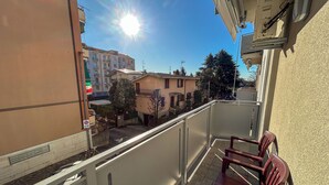 Un balcon donnant sur une rue résidentielle, un ciel dégagé et un vélo garé.
