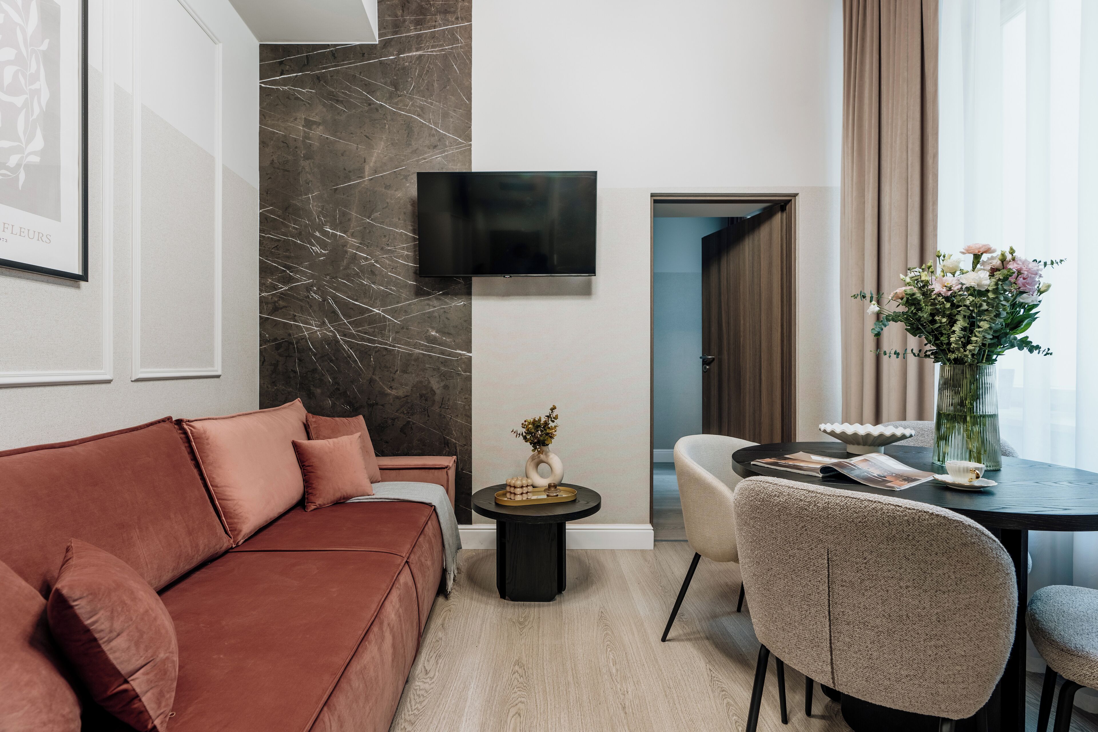 A modern living room with a brown sofa, a round coffee table, and a TV mounted on the wall.