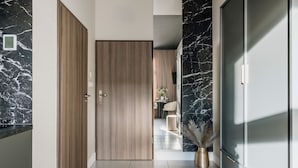 Een moderne hal met een houten deur, een marmeren wand en uitzicht op een eetruimte met een tafel en stoelen.