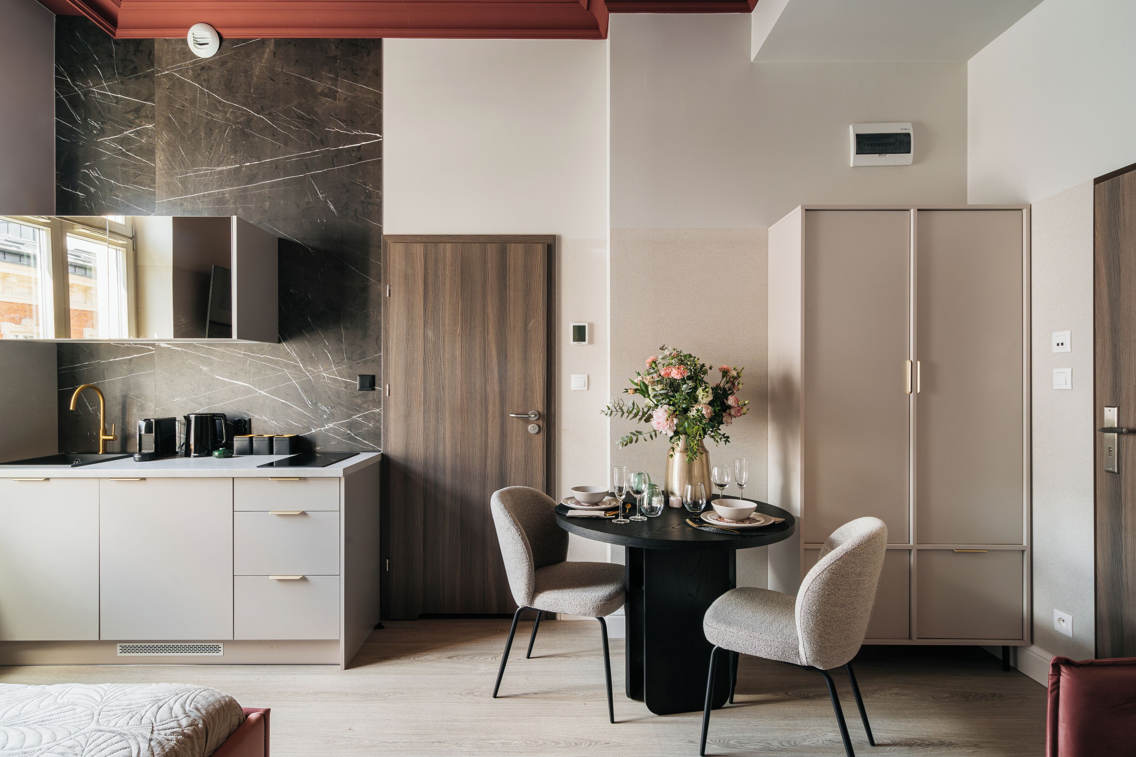 A modern kitchen with a marble backsplash, a dining area with a round table and chairs, and a built-in oven.