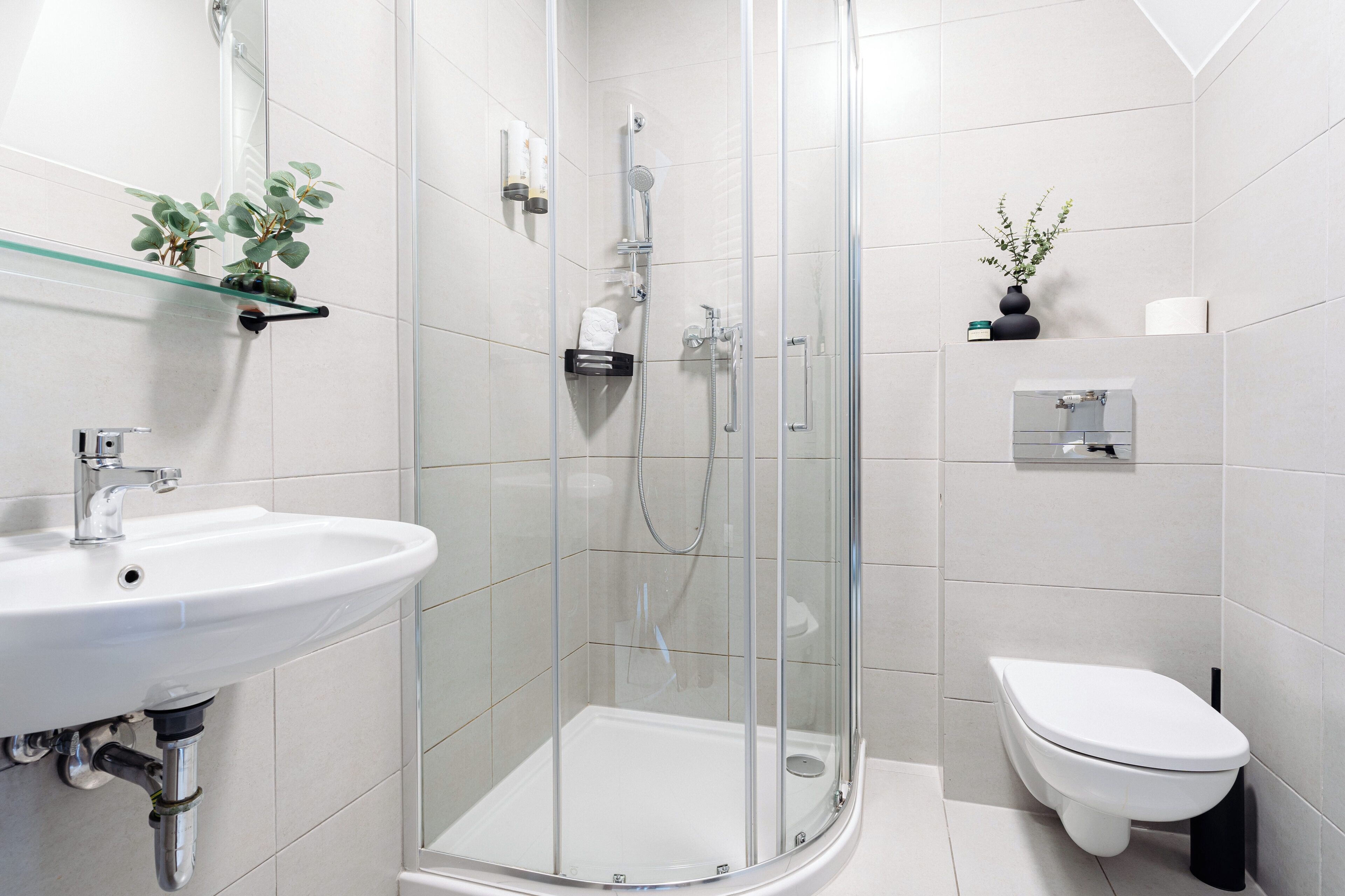 Un bagno moderno con doccia vetrata, lavandino bianco e water.