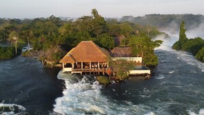 A riverside lodge with a thatched-roof structure, a pool, and a view of the river.