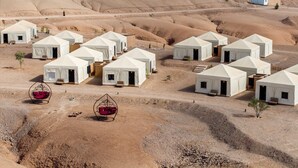 Un campo nel deserto con tende bianche disposte in file, ognuna con una porta e un piccolo oblò.