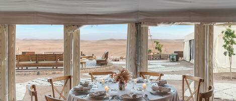 An outdoor dining area with a table set for six, overlooking a desert landscape.