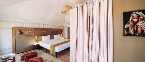 Una habitación con carpa, una cama, una mesita de noche y una lámpara colgante.
