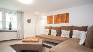 Ein modernes Wohnzimmer mit einer Sofagarnitur, einem Couchtisch und einer Stehlampe.