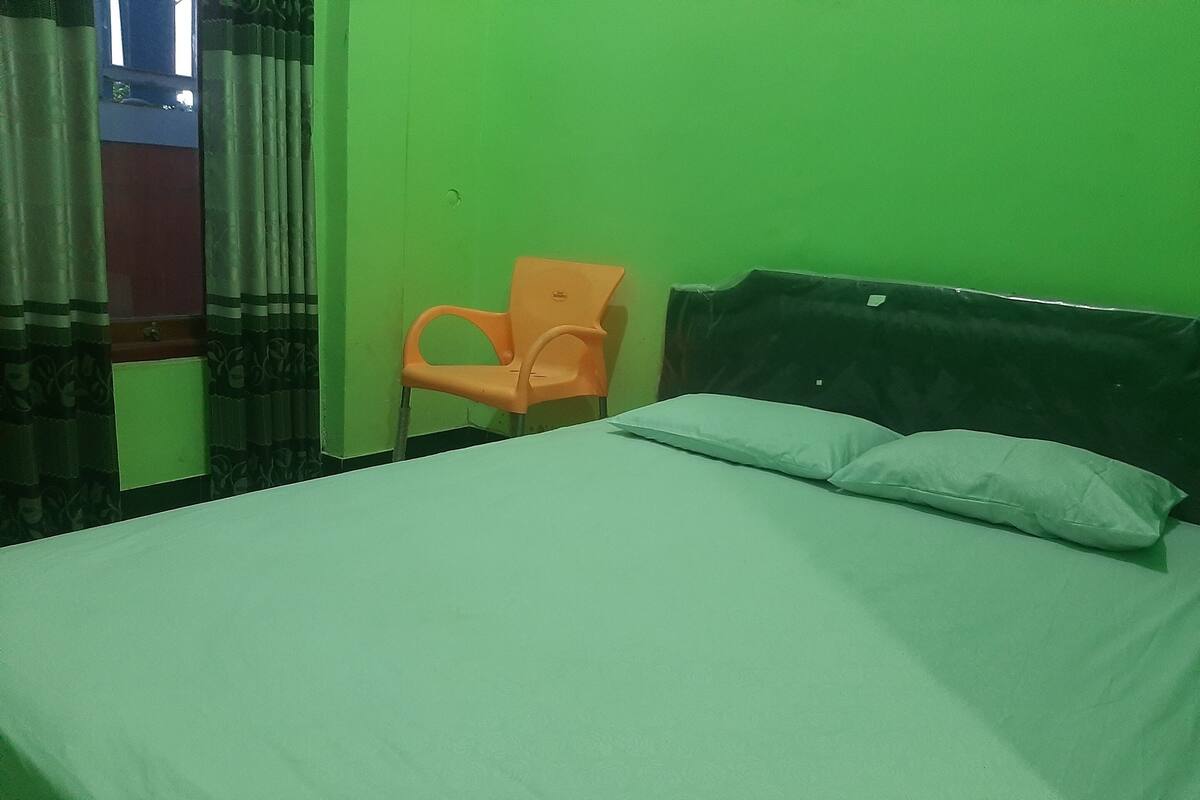 A room with a bed, a chair, and a green wall.