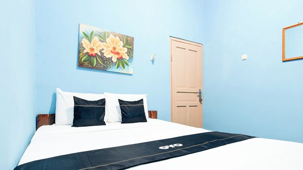 A bedroom with a bed, a door, and a painting on the wall.