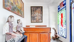 A reception desk with a sign reading "RECEPTION," a painting of a tiger, and a decorative window with a floral design.