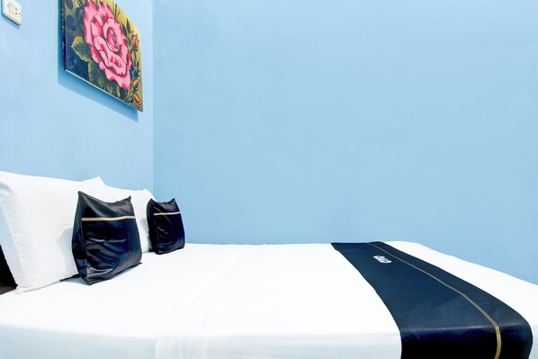 A bed with white and black bedding, a single black pillow, and a decorative pillow. - Capital O 94088 Anane Malioboro Homestay (Yogyakarta)