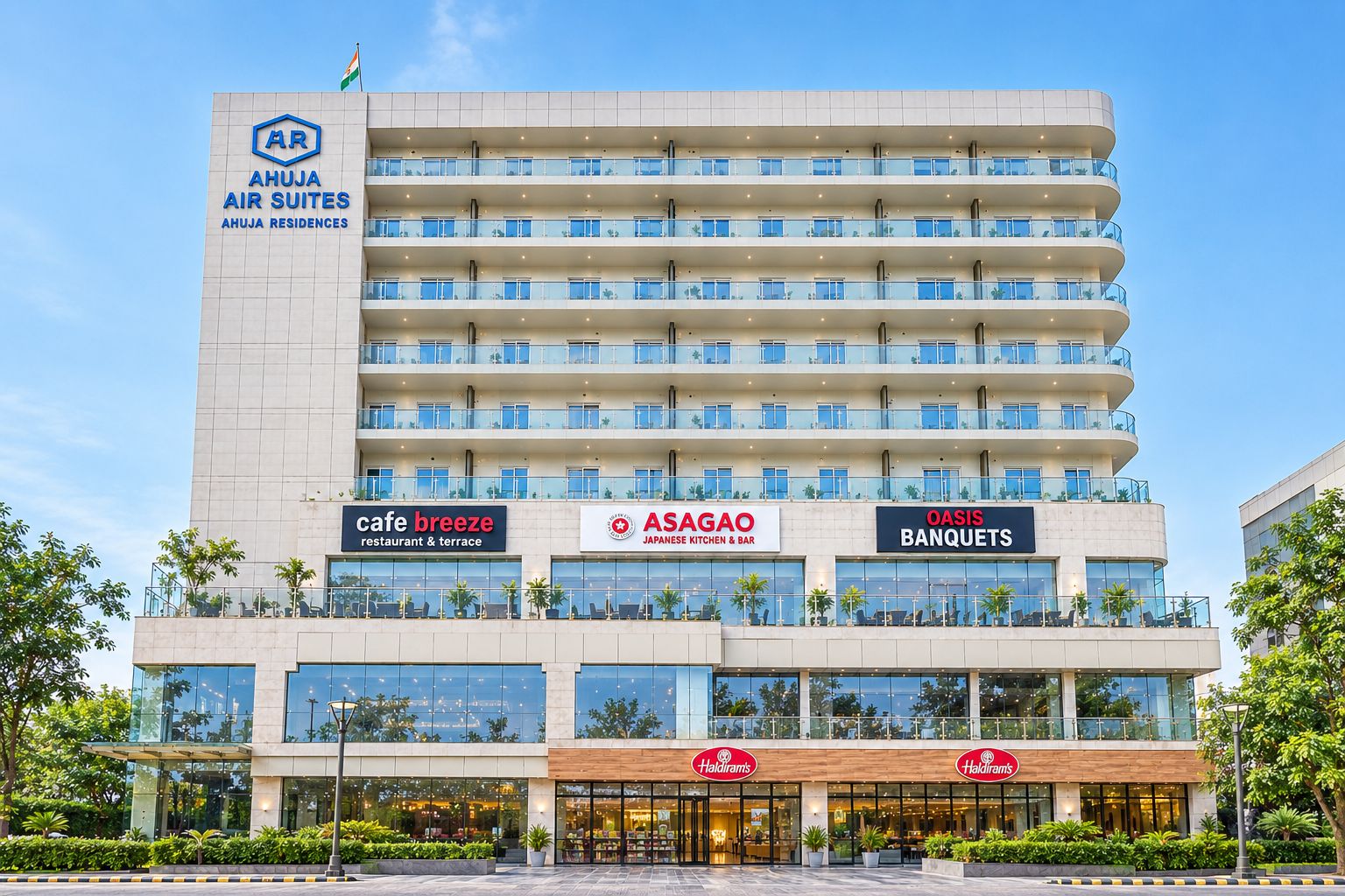 Un hotel de varios pisos con fachada plana, que destaca un cartel grande que dice 'AHUJA AIR SUITES' en la parte superior.