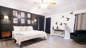 A bedroom with a bed, bedside tables, a desk, a chair, and wall decorations.