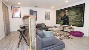 A modern living room with a grey sofa, a coffee table, a TV wall-mounted above a zebra print rug, and a projector screen.