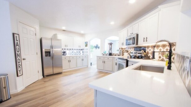 A modern kitchen with white cabinetry, stainless steel appliances, and a central island.