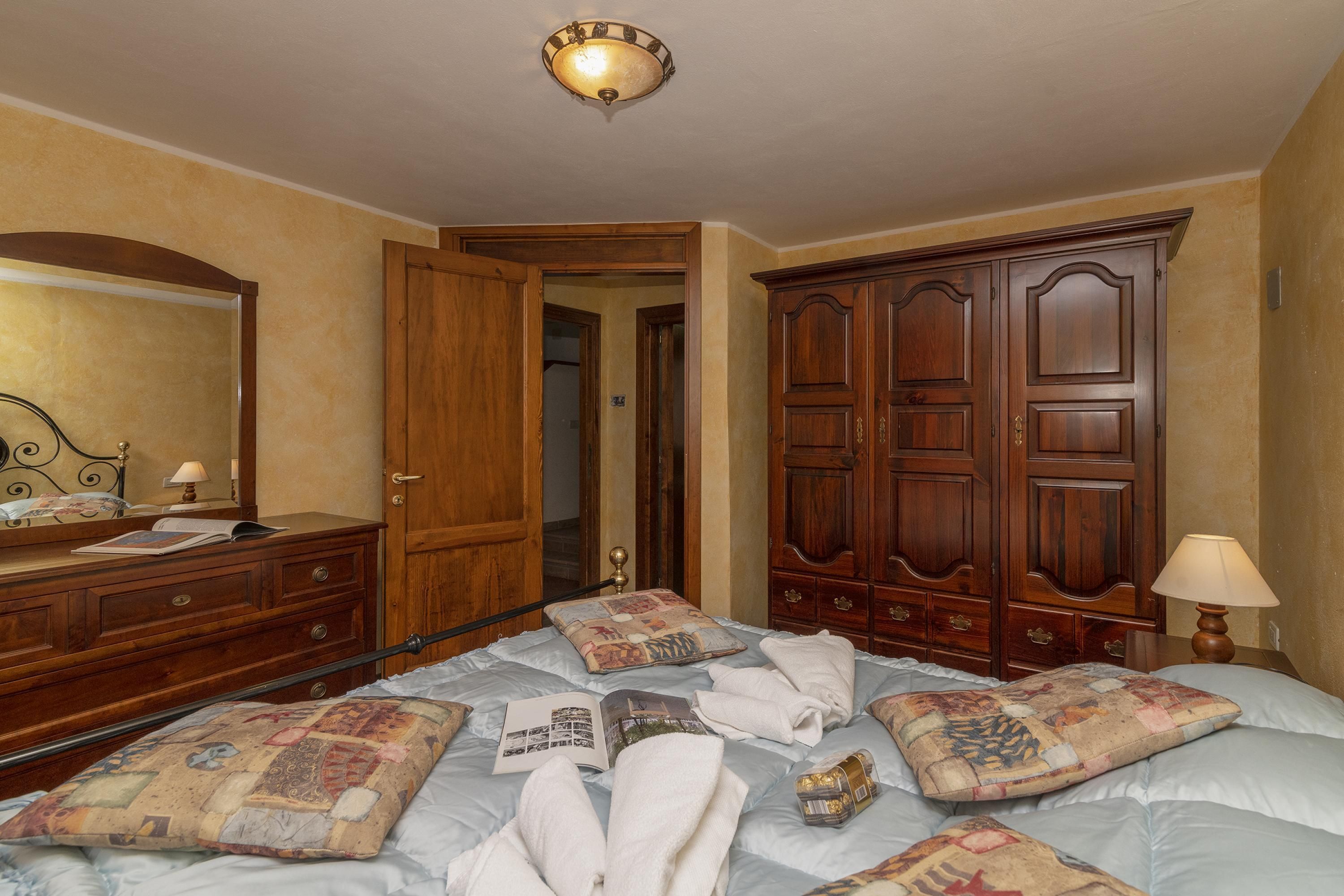 A hotel room with a bed, wooden wardrobe, and a mirror.