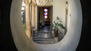 Ein rundes architektonisches Element rahmt eine Treppe, die zu einer Tür mit einem Buntglasfenster führt.
