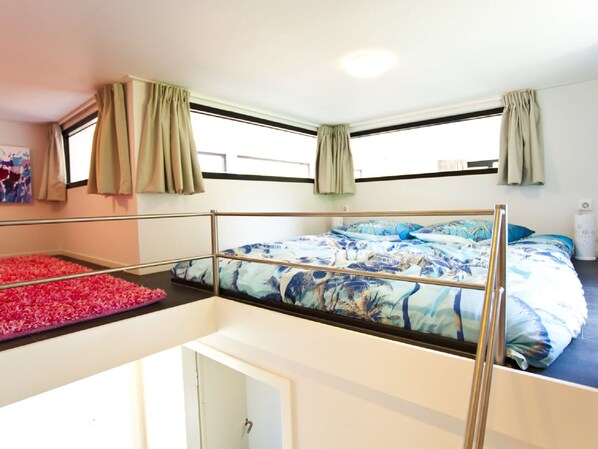 A room with a bunk bed, a window with curtains, a door, and a small white table. - Luxury Holiday Home on a Holiday Park, Adjacent to the Hoge Veluwe National Park (Arnhem)
