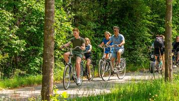A group of people riding bicycles on a paved path surrounded by lush greenery.