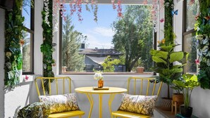 Een gezellige zithoek met gele stoelen en een kleine ronde tafel, omgeven door weelderige groene planten en bloemen.