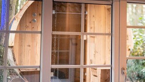 A wooden cabin with a large window, a door, and a view of the surrounding forest. - Luxe Villa met Wellness en Domotica (Soest)