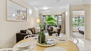 A dining area with a round table, chairs, a vase with greenery, and a painting on the wall. - Lux Resort - 9 Pools Gym Free Parking (Westcourt)