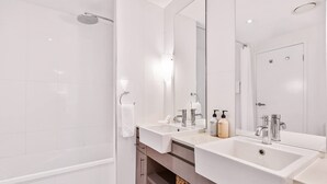 A modern bathroom with a walk-in shower, two sinks, and a large mirror.