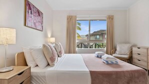 A hotel room with a bed, a nightstand, a chair, a window with curtains, and a view of a building outside. - Poolside Paradise Cairns - 9 Pools BBQ Gym (Westcourt)